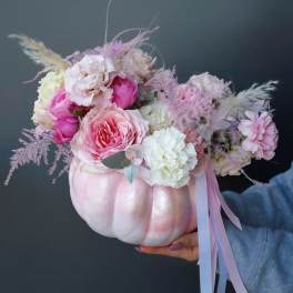 Pink and white floral arrangement in a painted pumpkin container