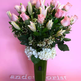 Pink roses and white lilies in a tall green vase