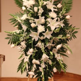 White funeral spray with lilies and roses on a standing easel