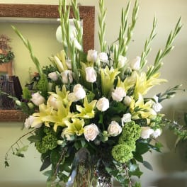 Tall bouquet of white roses and yellow lilies in a glass vase