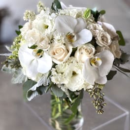 White bouquet of orchids and roses in a clear glass vase