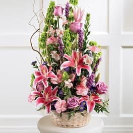 Tall basket arrangement with pink lilies, roses, and purple flowers