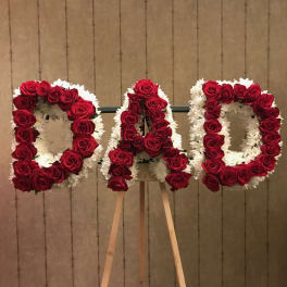 Floral tribute spelling "DAD" with red roses and white flowers on an easel