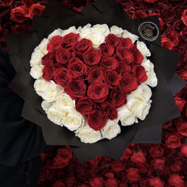 Heart-shaped bouquet of red and white roses wrapped in black paper