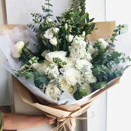 White rose bouquet with eucalyptus wrapped in brown paper