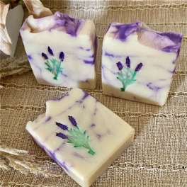 Three lavender and white decorative soap bars with pressed flowers