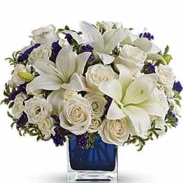 White lilies and roses arranged in a blue glass vase