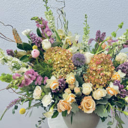 Large mixed floral arrangement in a round vase with pink, white, and peach blooms
