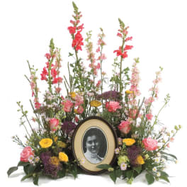 Floral memorial arrangement with a framed portrait in the center