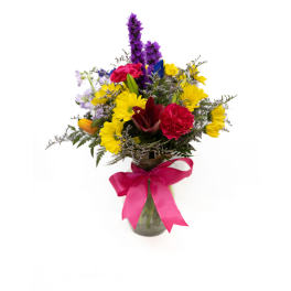 Mixed bouquet in a glass vase with a pink ribbon