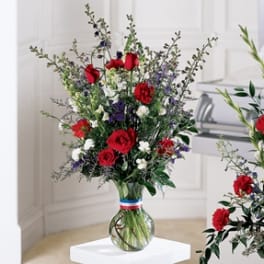 Tall bouquet of red, white, and purple flowers in a glass vase