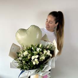 Woman holding a large white flower bouquet with a heart balloon