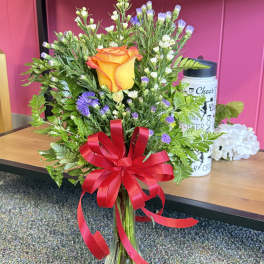 Orange rose bouquet in a clear glass vase with a red ribbon