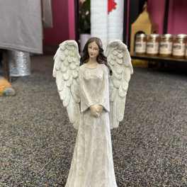 White angel figurine with large wings standing on a carpeted floor