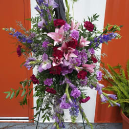Tall floral spray with pink lilies and purple flowers on a stand