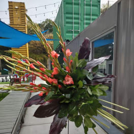 Large floral spray with coral blooms and dark leaves on a stand