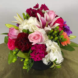 Mixed bouquet of pink, white, purple, and red flowers in a black vase