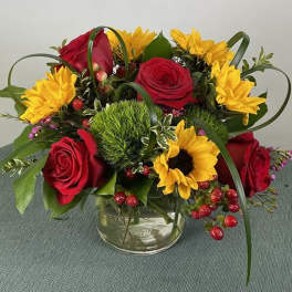 Bouquet of red roses and yellow sunflowers in a clear glass vase