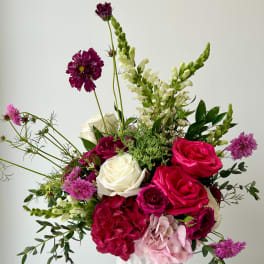 Mixed bouquet of pink, white, and purple flowers in a white vase
