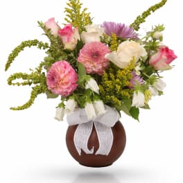 Bouquet of pink and white flowers in a brown vase with a white ribbon