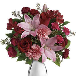Pink lilies and red roses arranged in a clear glass vase