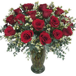 Red roses arranged in a clear glass vase with small white filler flowers
