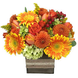 Orange and yellow mixed flower arrangement in a square wooden box