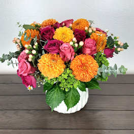 Bouquet of orange dahlias and pink roses in a white vase