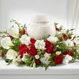 Red roses and white calla lilies arranged around a white urn