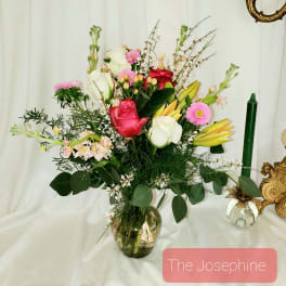 Mixed bouquet of roses, lilies, and pink daisies in a glass vase