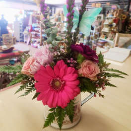 Mixed bouquet in a decorative tin with pink and purple flowers and butterfly picks