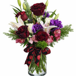 Bouquet of red roses, white lilies, and purple flowers in a glass vase