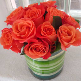 Orange roses arranged in a striped glass vase