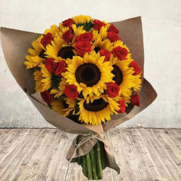 Bouquet of sunflowers and red roses wrapped in brown paper
