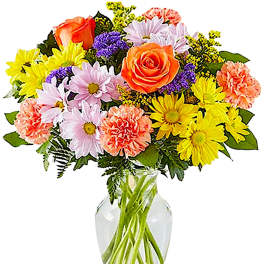 Mixed bouquet of roses, daisies, and carnations in a clear glass vase
