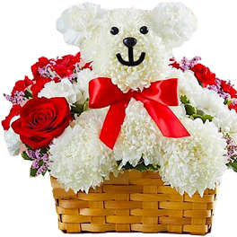 White teddy bear in a basket surrounded by red and white flowers