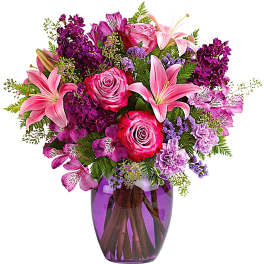 Pink and purple mixed bouquet in a purple glass vase