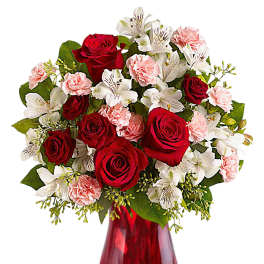 Red roses, white lilies, and pink carnations in a red glass vase