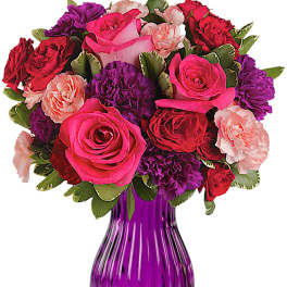 Bouquet of pink, red, and purple flowers in a purple glass vase