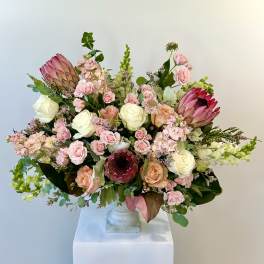 Large pastel bouquet with roses and protea in a white vase