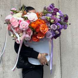 Large bouquet of pink, orange, and purple flowers in a white box