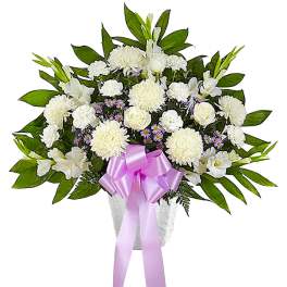 White floral arrangement with a pink ribbon in a vase