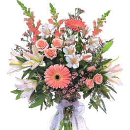 Bouquet of pink and white flowers in a glass vase with a lavender ribbon