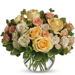 Bouquet of cream, peach, and yellow roses in a glass vase