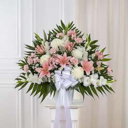 Pink and white floral spray with a white ribbon bow in a vase