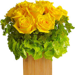 Yellow roses arranged in a wooden square vase with green hydrangea