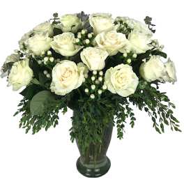 White roses arranged in a dark glass vase with trailing greenery