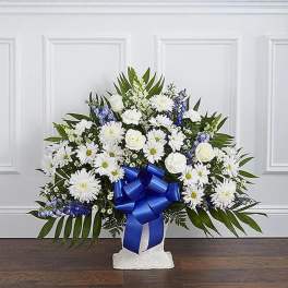 White floral standing spray with a blue ribbon on a pedestal base