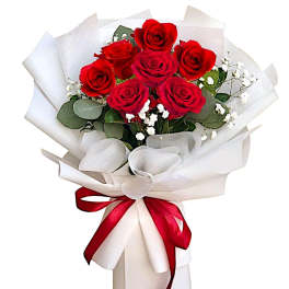 Bouquet of red roses wrapped in white paper with a red ribbon