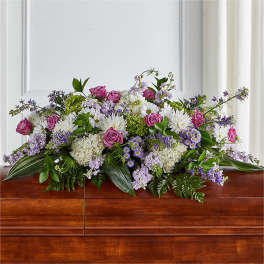 Large floral casket spray with pink roses, white daisies, and purple blooms
